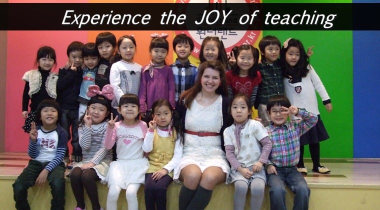 a smiling TEFL teacher and many korean kindergarten students